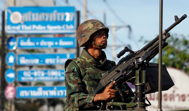 A Thai soldier mans a machine gun as his unit takes position in central Bangkok