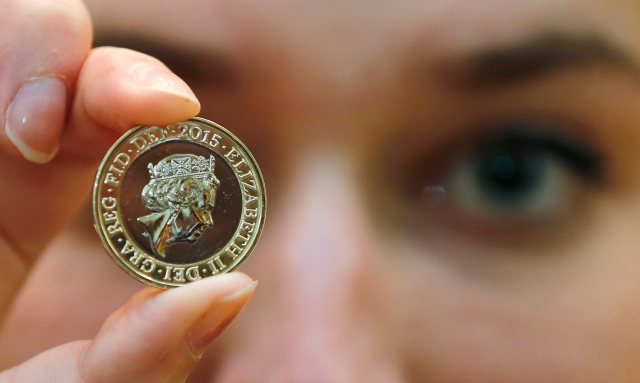 A gallery assistant poses with a 2-pound coin with the new portrait of Britain's Queen Elizabeth following it's unveiling at the National Portrait Gallery in London