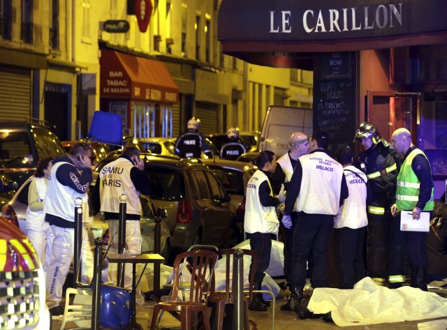 Rescue service personnel work near the covered bodies outside a restaurant following a shooting incident in Paris