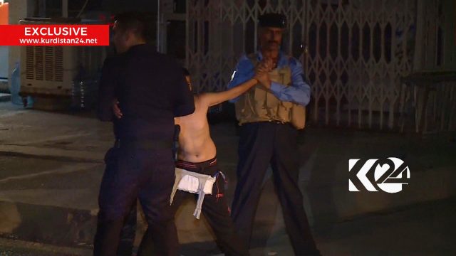 Imagen tomada de la señal de una televisota local que muestra a un niño siendo detenido por elementos de seguridad, uno de los cuales corta un cinturón con explosivos, la noche del domingo 21 de agosto de 2016, en Kirkuk, Irak. (Canal 24 de la TV de Kurdistán vía AP) CRÉDITO OBLIGATORIO