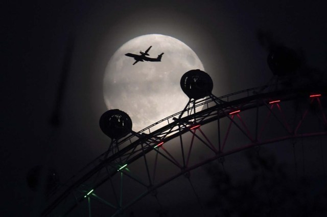An aeroplane flies past the London Eye wheel, and moon, a day before the "supermoon" spectacle in London, Britain, November 13, 2016. REUTERS/Toby Melville