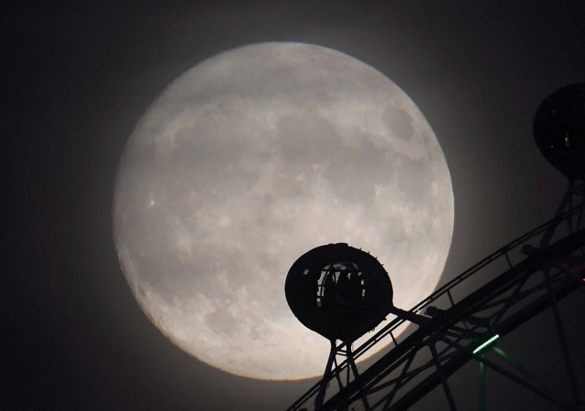 The moon is seen behind the London Eye wheel a day before the "supermoon" spectacle in London, Britain, November 13, 2016. REUTERS/Toby Melville