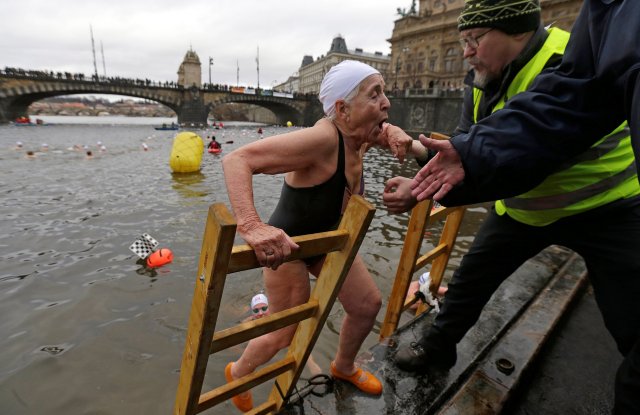 A swimmer is helped out of the Vltava river after the annual Christmas winter swimming competition in Prague, Czech Republic, December 26, 2016. REUTERS/David W Cerny