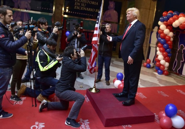 Medias film and take pictures of the wax statue of US President-elect Donald Trump during its presentation at the Wax Museum of Madrid on January 17, 2017. / AFP PHOTO / GERARD JULIEN