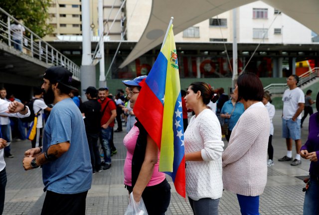 A woman holds a national flag as she stands in line along with others to cast her vote during an unofficial plebiscite against Venezuela's President Nicolas Maduro's government and his plan to rewrite the constitution, in Caracas, Venezuela July 16, 2017. REUTERS/Andres Martinez Casares