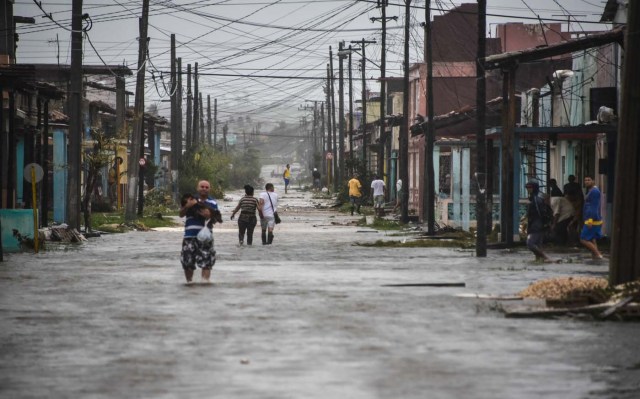 Locals wade through a flooded street after the passage of Hurricane Irma, at Caibarien, Villa Clara province, 330km east of Havana, on September 9, 2017. Irma's blast through the Cuban coastline weakened the storm to a Category Three, but it is still packing 125 mile-an-hour winds (205 kilometer per hour) and was expected to regain power before hitting the Florida Keys early Sunday, US forecasters said. The Cuban government extended its maximum state of alert to three additional provinces, including Havana, amid fears of flooding in low-lying areas. / AFP PHOTO / ADALBERTO ROQUE