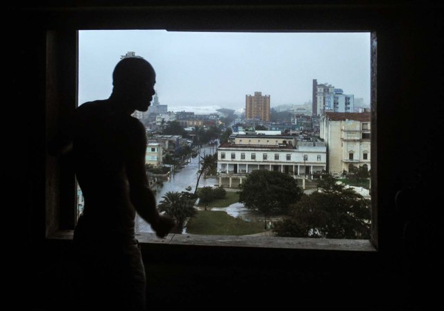 A man looks from the window at flooded streets, during the passage of Hurricane Irma in Havana, on September 9, 2017. Irma's blast through the Cuban coastline weakened it to a Category Three, but it is still packing winds of 125 miles (200 kilometer) per hour. / AFP PHOTO / YAMIL LAGE
