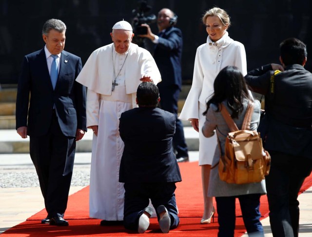 A faithful kneels as Colombia's President Juan Manuel Santos (L), First Lady Maria Clemencia Rodriguez (R) and Pope Francis arrive at Narino presidential palace in Bogota, Colombia September 7, 2017. REUTERS/Stefano Rellandini