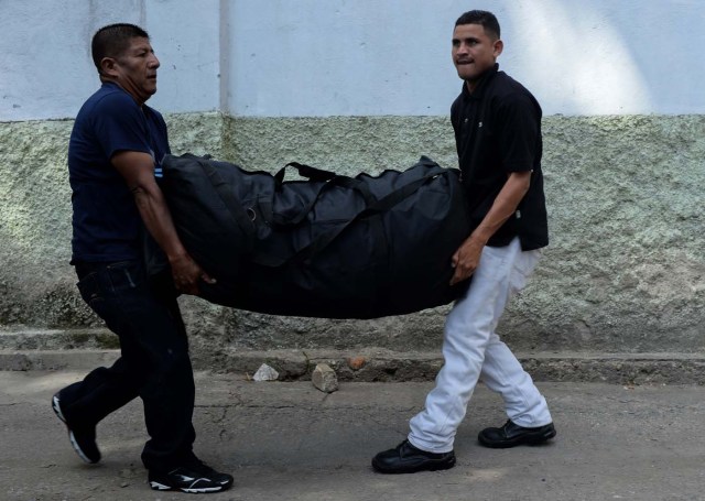 Two men carry a bag as they arrive at a bus station in Caracas on October 11, 2017 as scores of disappointed Venezuelans who see no end to the crisis choose to leave the country. Venezuela, which holds regional elections on October 15, is a country at the top of the Latin American continent that is in deep economic and political crisis. / AFP PHOTO / Federico PARRA