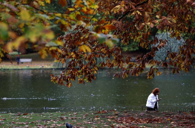 A woman takes a photograph amongst the autumn leaves in St. James's Park in London, Britain October 20, 2017. REUTERS/Peter Nicholls