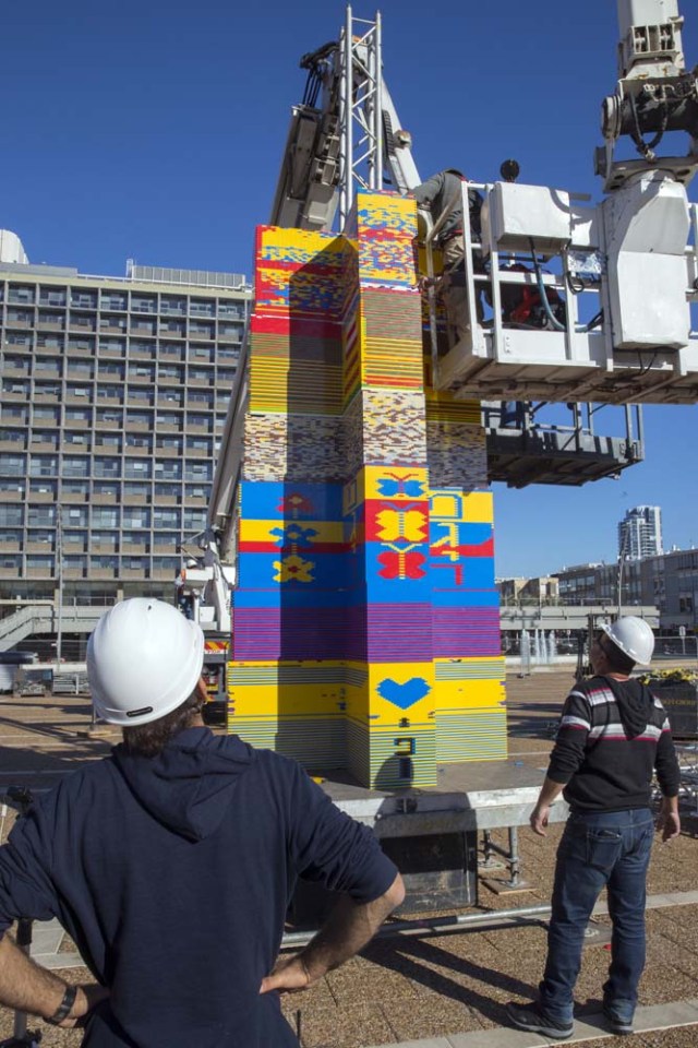 Workers and volunteers help assemble bricks during the construction of a LEGO tower in Tel Aviv's Rabin Square on December 26, 2017, as the city attempts to break Guinness world record of the highest such structure. / AFP PHOTO / JACK GUEZ