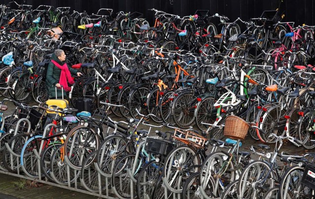 A woman pulls her luggage while walking among hundreds of bicycles outside central train station in Amsterdam, Netherlands, December 1, 2017. REUTERS/Yves Herman