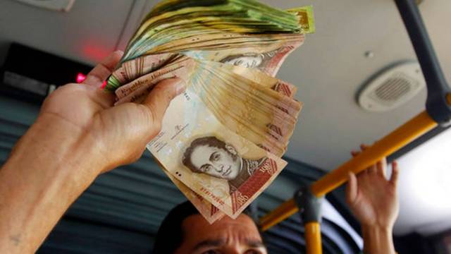El venezolano Jorge Gutiérrez sostiene un fajo de billetes venezolanos sin apenas valor que quiere cambiar por dinero colombiano, en un autobús de Bogotá, Colombia, el martes 12 de diciembre de 2017. Fernando Vergara AP Foto