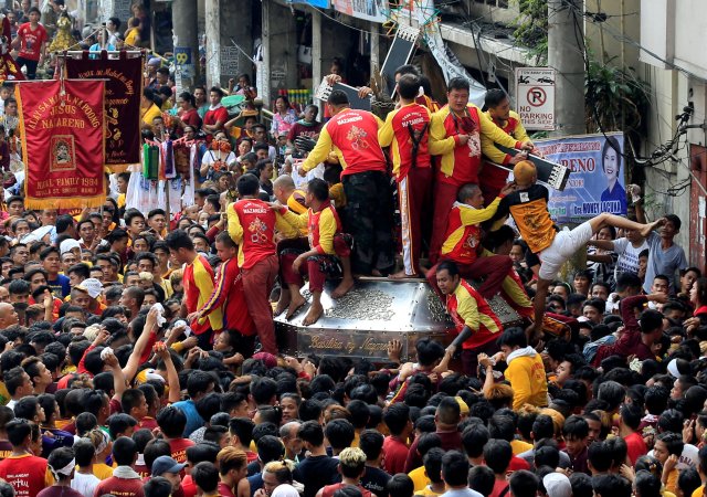 Devotees climb on a carriage to hold the Black Nazarene replica during an annual procession in Quiapo city, Metro Manila, Philippines January 7, 2018. REUTERS/Romeo Ranoco