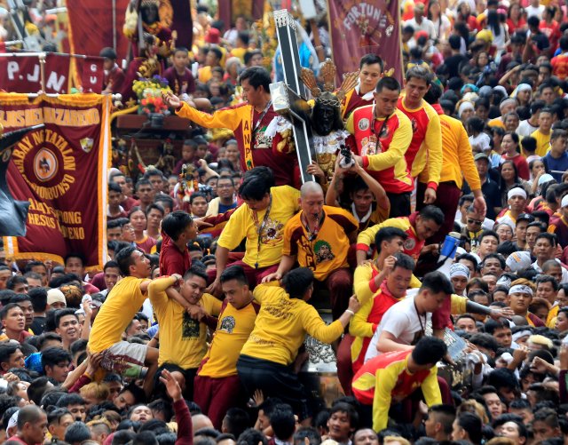 Devotees climb on a carriage to hold the Black Nazarene replica during an annual procession in Quiapo city, Metro Manila, Philippines January 7, 2018. REUTERS/Romeo Ranoco
