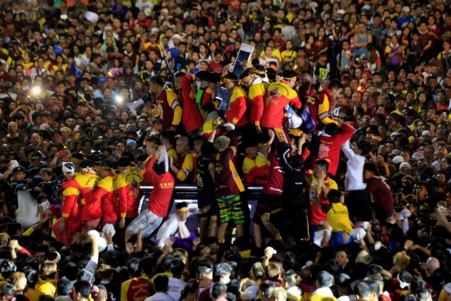 Devotees climb on a carriage to hold the image of the Black Nazarene during an annual procession at Luneta grandstand, Metro Manila, Philippines January 9, 2018. REUTERS/Romeo Ranoco