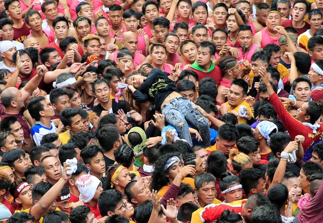 Devotees carry a woman who fainted after attempting to reach the carriage of the image of the Black Nazarene as they participate in the annual procession at Chinatown, Metro Manila, Philippines January 9, 2018. REUTERS/Romeo Ranoco