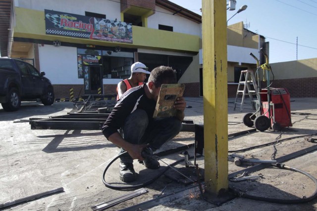Workers repair the fence of a supermarket, after it was looted in Puerto Ordaz, Venezuela January 9, 2018. REUTERS/William Urdaneta