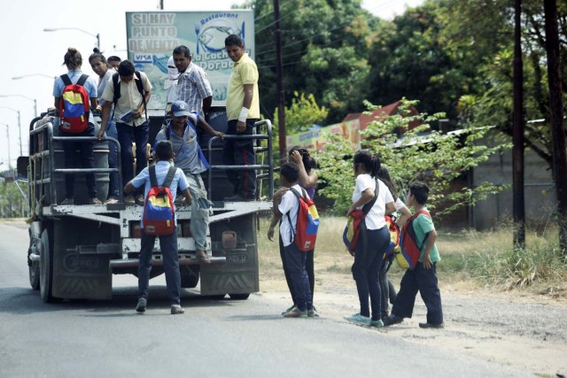 Los escolares se suben a la parte trasera de un camión camino a la escuela en Socopo, Venezuela, el 1 de marzo de 2018. Foto tomada el 1 de marzo de 2018. REUTERS / Carlos Eduardo Ramirez