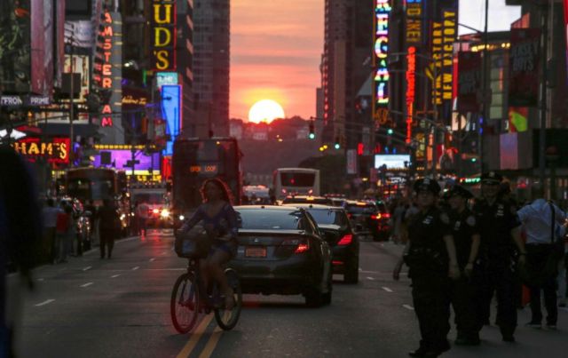 A woman rides a bike on 42nd Street in New York City during Manhattanhenge | Foto: AFP